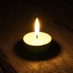 Burning candle. On wooden background.