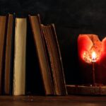 Vintage books and candle on dark background
